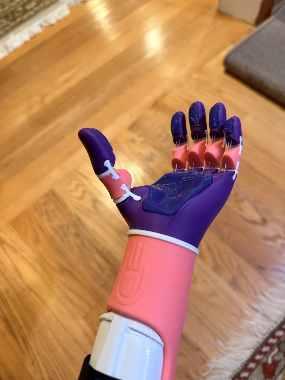 Close view of the finished hand resting on a wood floor — purple fingers articulated
